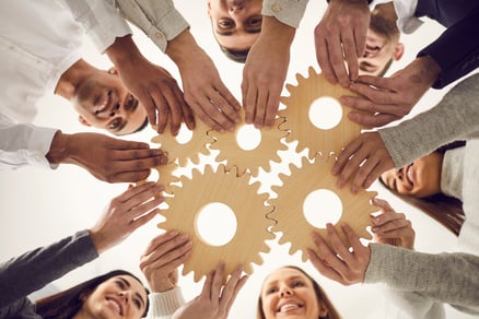 employees work together to fit gears together demonstrating employee benefits