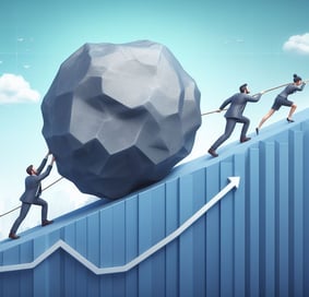 businesspeople pushing and pulling a boulder up a hill