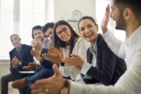employees clap for a coworker giving him peer-to-peer recognition
